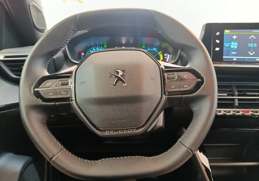 Volant cuir noir multifonctions de Peugeot E-2008 électrique, vue frontale centrée sur le tableau de bord digital.