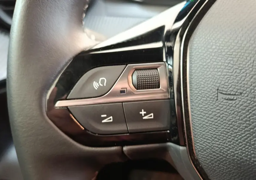 Gros plan sur les commandes multifonctions du volant cuir noir du Peugeot E-2008 électrique Active Pack 2023.