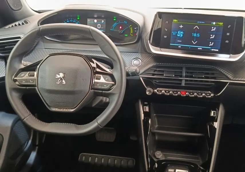 Vue intérieure centrée sur le volant cuir multifonctions et le tableau de bord numérique du Peugeot E-2008 électrique gris.