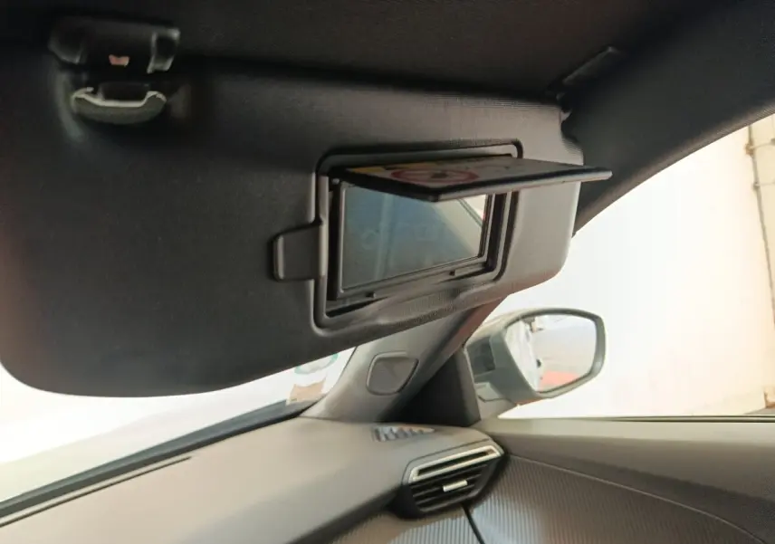 Vue intérieure côté passager du Peugeot E-2008 électrique gris clair, avec pare-soleil et miroir de courtoisie ouverts.