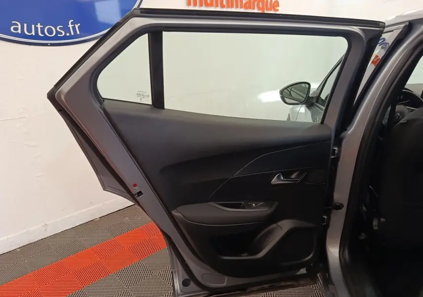 Vue intérieure de la porte arrière gauche gris clair d’un Peugeot E-2008 électrique 2023, avec garniture noire et poignée argentée.