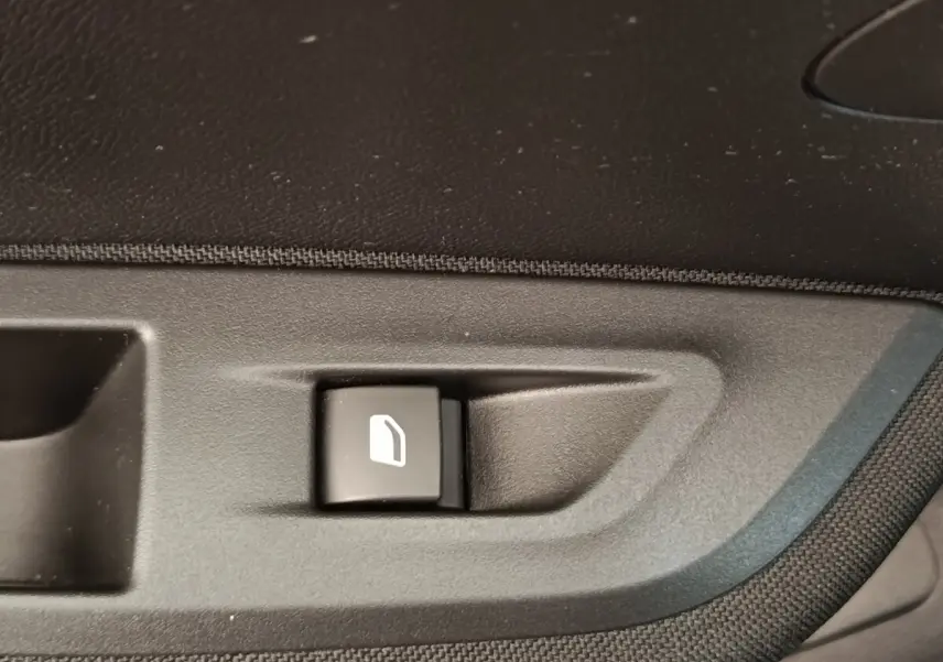 Bouton de commande de lève-vitre sur la portière intérieure côté conducteur du Peugeot E-2008 électrique gris clair 2023.