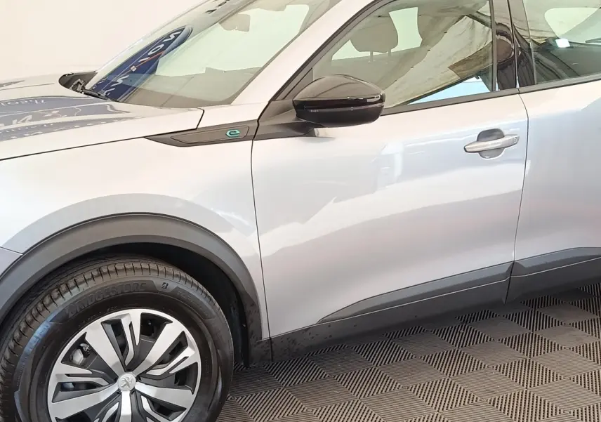 Vue de profil côté gauche du Peugeot E-2008 électrique gris clair avec jante et rétroviseur noir brillant.