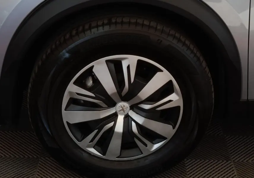 Gros plan sur la roue avant droite du Peugeot E-2008 électrique gris clair avec jante alliage au design moderne.