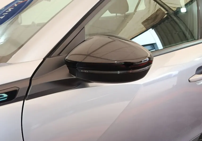 Gros plan sur le rétroviseur droit noir brillant du Peugeot E-2008 électrique gris clair, côté avant du véhicule.