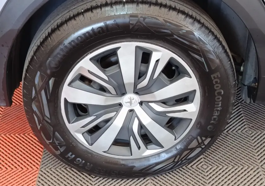 Gros plan sur la roue avant droite de la Peugeot E-2008 électrique gris clair avec jante alliage et pneu Continental.