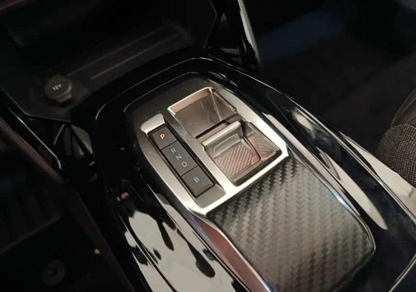 Gros plan sur la console centrale noire brillante avec sélecteur de vitesses électronique du Peugeot E-2008 électrique gris clair.