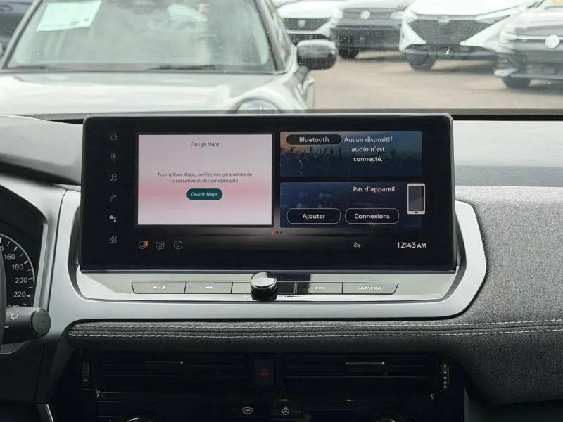 Vue frontale de l'écran tactile central du tableau de bord du Nissan Qashqai blanc nacré 2025 avec interface multimédia affichée.