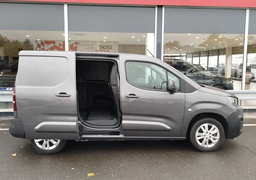 Vue latérale droite d’un Peugeot Partner gris foncé 2020 avec porte coulissante ouverte, montrant l’espace de chargement vide.