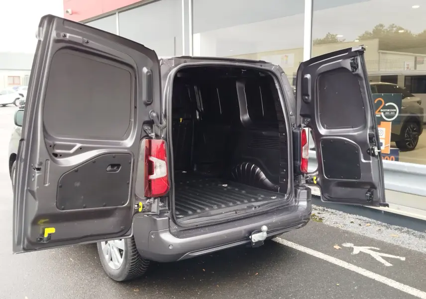 Vue arrière 3/4 droit d'un Peugeot Partner gris foncé avec portes arrière ouvertes montrant l'espace de chargement vide.
