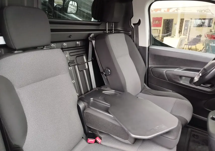 Vue intérieure côté droit du Peugeot Partner 2020 gris foncé, montrant les sièges avant et une tablette rabattable centrale.
