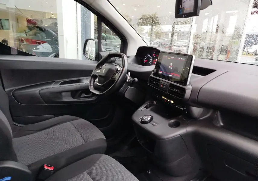 Vue intérieure côté conducteur du Peugeot Partner 2020 gris foncé, avec tableau de bord et écran tactile central visibles.