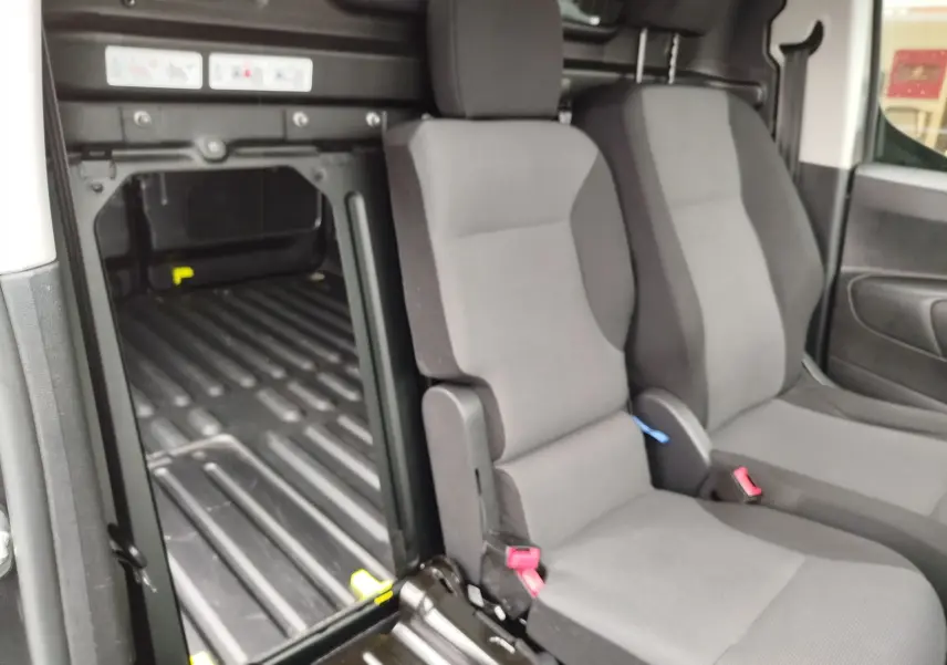 Vue intérieure côté droit du Peugeot Partner 2020, montrant les sièges avant gris et l’espace de chargement vide.