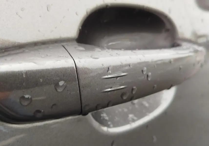 Poignée de porte gris foncé du Peugeot Partner 2020 avec gouttes d'eau, vue rapprochée sur le côté droit.