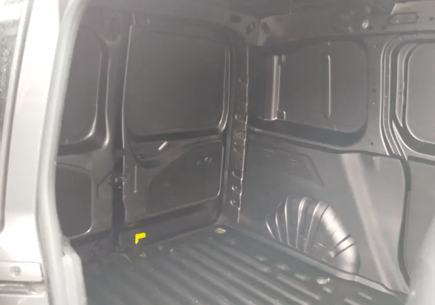 Vue intérieure de la zone de chargement du Peugeot Partner gris foncé, montrant les parois métalliques et le plancher strié.