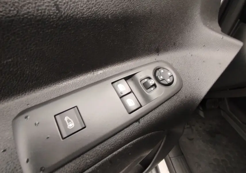 Gros plan sur les commandes de réglage des vitres et des rétroviseurs côté conducteur du Peugeot Partner gris foncé 2020.