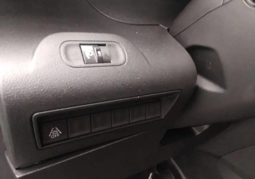 Détail intérieur montrant les commandes de réglage des phares et l'activation du système d'alerte de franchissement de ligne sur Peugeot Partner gris.