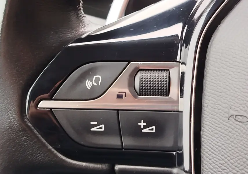 Gros plan sur les commandes de volume et de téléphone intégrées au volant en cuir noir du Peugeot Partner gris foncé 2020.