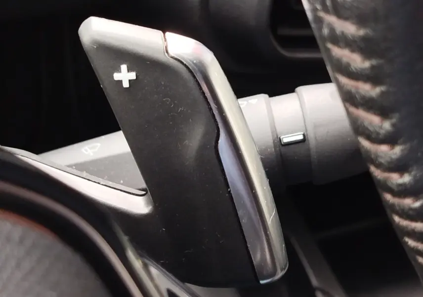 Gros plan sur la palette de passage de vitesse "+" en plastique noir et chrome, à droite du volant du Peugeot Partner gris foncé.