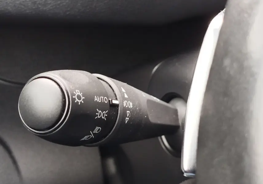 Gros plan sur la commande des phares à gauche du volant dans l’habitacle gris foncé du Peugeot Partner 2020.