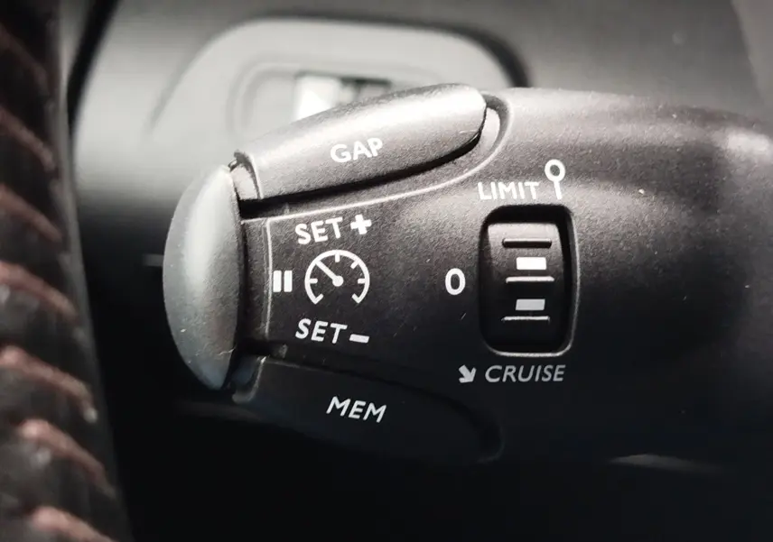 Gros plan sur la commande de régulateur de vitesse du Peugeot Partner 2020, intérieur noir, détails blancs visibles.