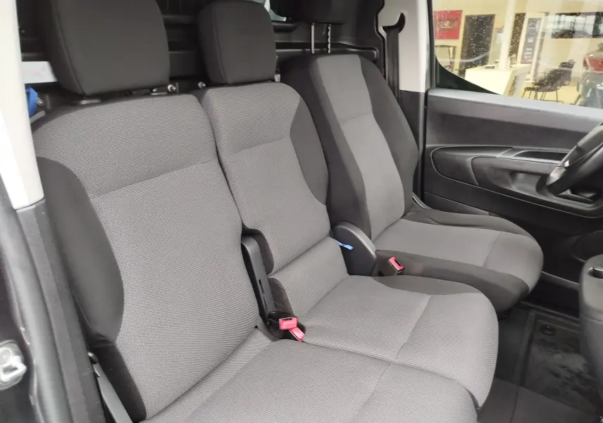 Vue intérieure côté droit montrant les sièges avant gris foncé du Peugeot Partner 2020 avec banquette passager triple.