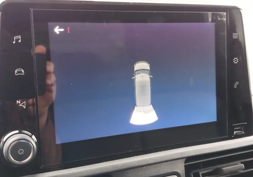 Écran tactile intérieur montrant l'affichage de la caméra de recul du Peugeot Partner gris foncé, vue de dessus du véhicule.