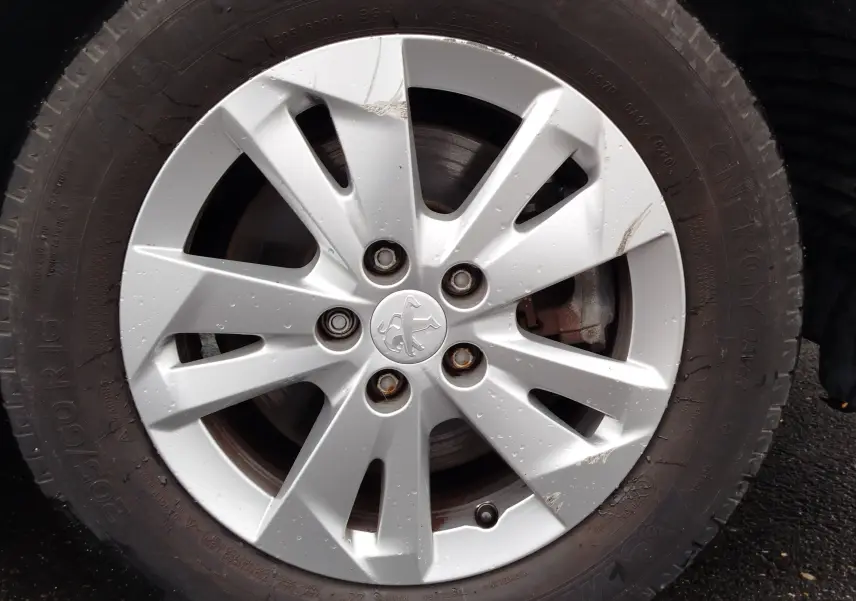 Gros plan sur la jante argentée d’un Peugeot Partner 2020, avec logo lion au centre et traces de boue sur le pneu noir.