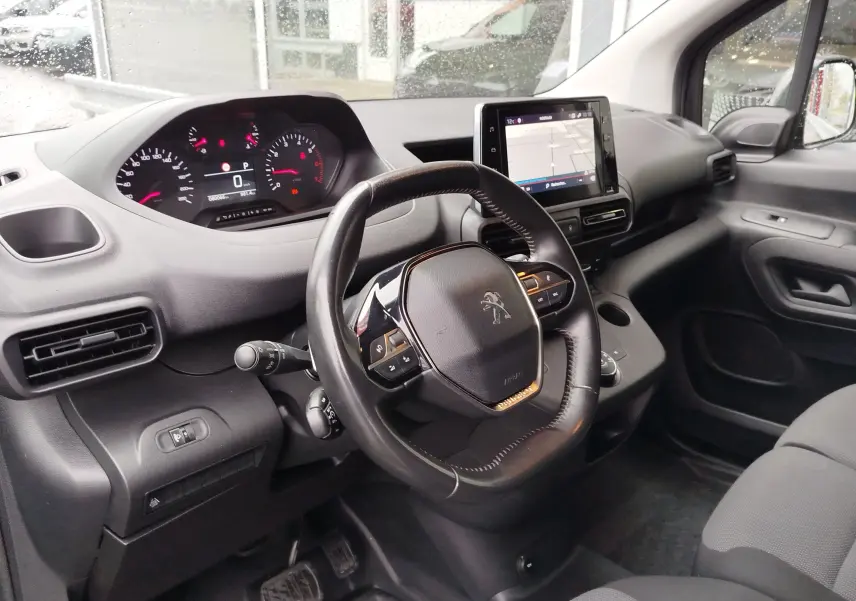 Vue intérieure côté conducteur du Peugeot Partner 2020, tableau de bord noir avec écran tactile et volant multifonction.