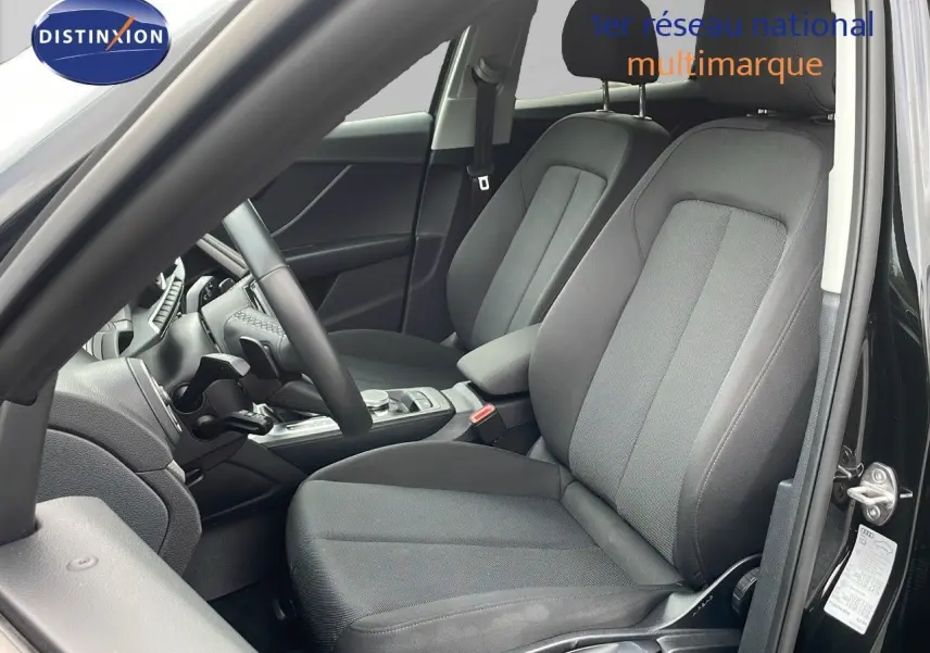 Vue intérieure côté conducteur de l'Audi Q2 35 TFSI S-Line 2023 avec sièges tissu gris et tableau de bord noir.