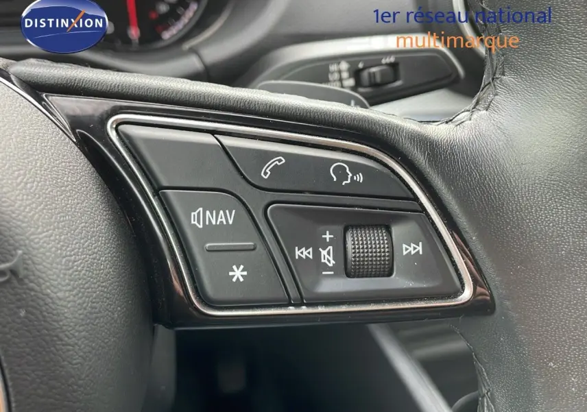 Gros plan sur les commandes multimédia et navigation au volant cuir d'un Audi Q2 noir mito metal 2023.