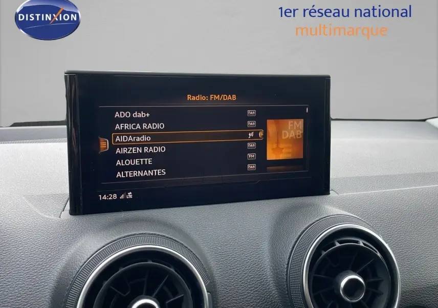 Écran central tactile affichant les stations radio FM/DAB dans l'habitacle d'un Audi Q2 noir mito metal.