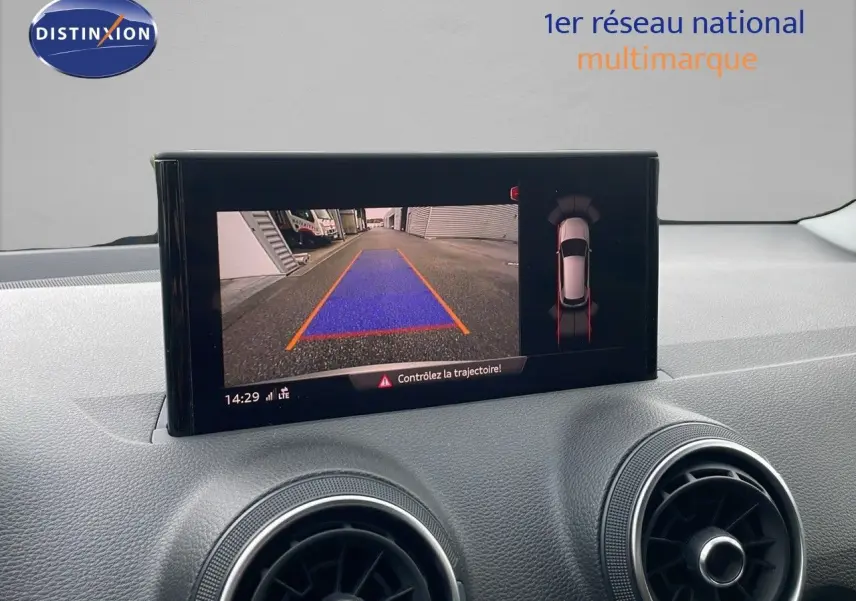 Écran multimédia affichant la caméra de recul et l'aide au stationnement d'un Audi Q2 noir mito metal, intérieur moderne.
