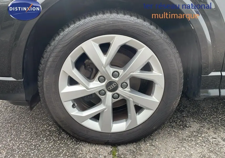 Gros plan sur la roue avant gauche d'un Audi Q2 noir mito metal avec jante argentée en alliage.