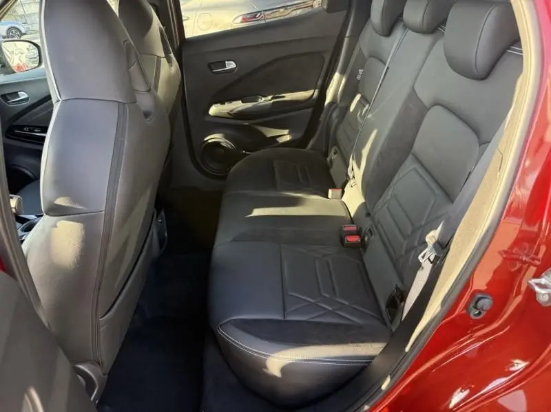 Vue intérieure côté droit des sièges arrière en cuir noir du Nissan Juke 2024 rouge Fuji métal avec toit noir.