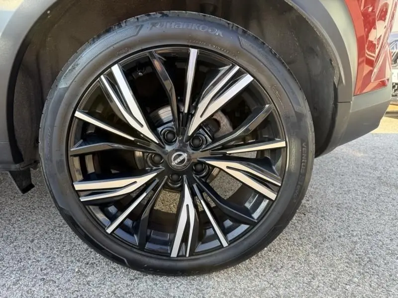 Gros plan sur la roue avant droite du Nissan Juke 2024 rouge Fuji avec jante alliage noir et argentée design dynamique.