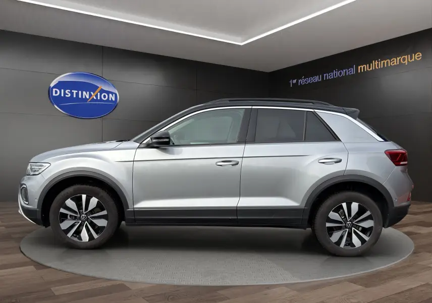Vue latérale droite du Volkswagen T-Roc 2025 gris Pyrite avec toit noir et jantes alu 17 pouces en showroom.