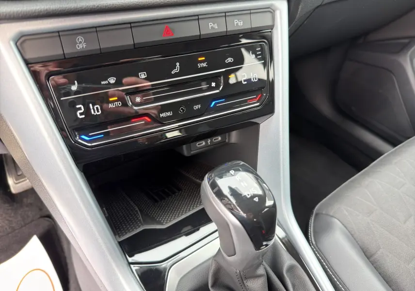 Gros plan sur la console centrale du Volkswagen T-Roc 2025, avec commandes climatisation digitale et levier de vitesse automatique.