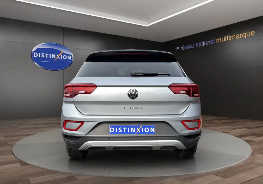 Vue arrière du Volkswagen T-Roc gris Pyrite avec toit noir, mettant en valeur ses feux LED et son attelage amovible.