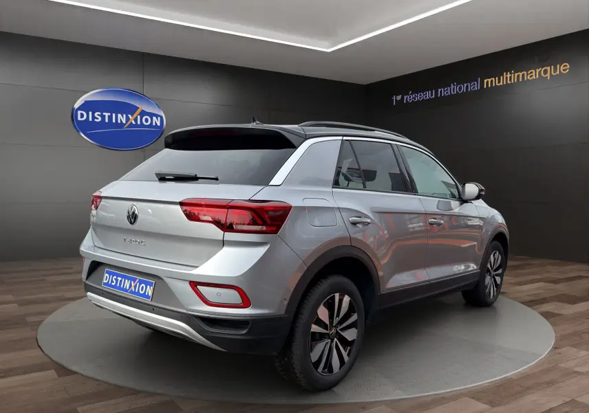 Volkswagen T-Roc gris Pyrite avec toit noir, vue 3/4 arrière droit, attelage amovible visible, jantes alu 17 pouces.