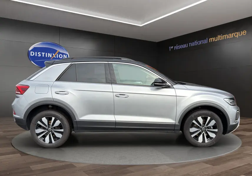 Vue de profil droit du Volkswagen T-Roc gris pyrite avec toit noir et jantes alliage 17 pouces en showroom.