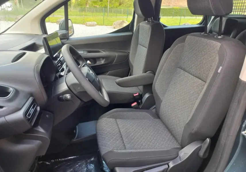 Vue intérieure côté conducteur de l'Opel Combo Life bleu 2025, montrant les sièges tissu gris et le tableau de bord moderne.