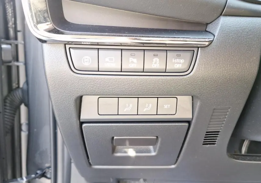 Gros plan sur les commandes de réglages et assistances situées à gauche du volant dans l'habitacle gris du Mazda3 2020.