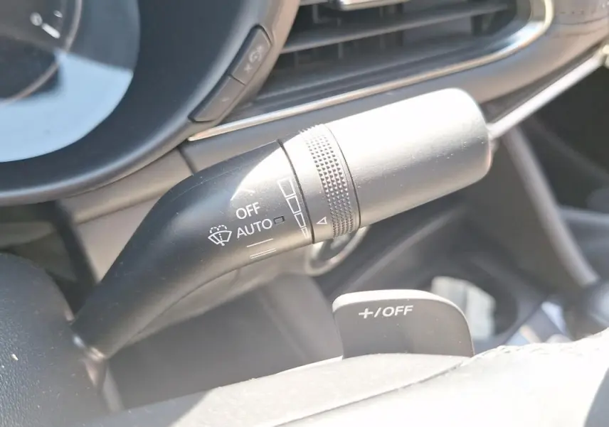 Gros plan sur la manette de commande des essuie-glaces à gauche du volant cuir dans l’habitacle gris de la Mazda3 2020.
