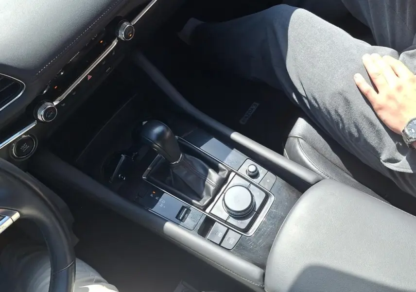 Vue rapprochée de la console centrale noire de la Mazda3 2020 avec levier de vitesse automatique et commandes multifonctions.