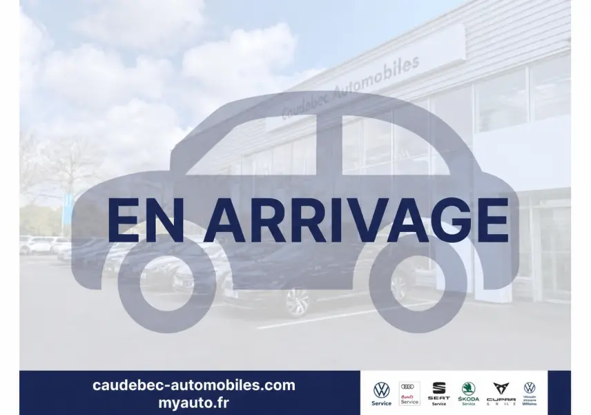 Vue 3/4 avant d’un Volkswagen Touran gris stationné devant un bâtiment de concession automobile.