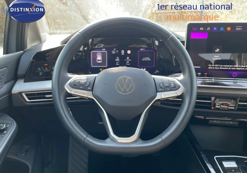 Vue intérieure centrée sur le volant cuir noir et les écrans digitaux du tableau de bord de la Volkswagen Golf SW gris lunaire.