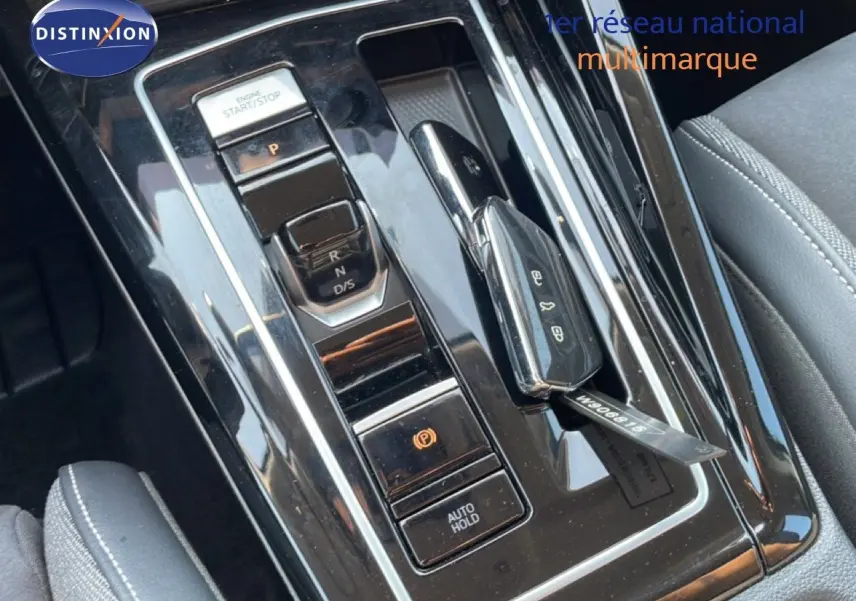 Gros plan sur la console centrale noire brillante de la Volkswagen Golf SW VIII 2024 avec clé de contact posée.