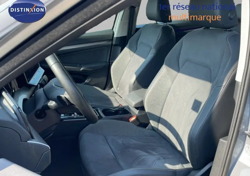 Vue intérieure côté conducteur de la Volkswagen Golf SW VIII gris lunaire, sièges en tissu et cuir gris avec volant multifonction.