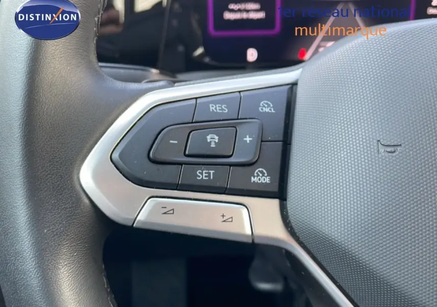 Gros plan sur les commandes au volant à gauche de la Volkswagen Golf SW VIII gris lunaire, avec régulateur de vitesse adaptatif.